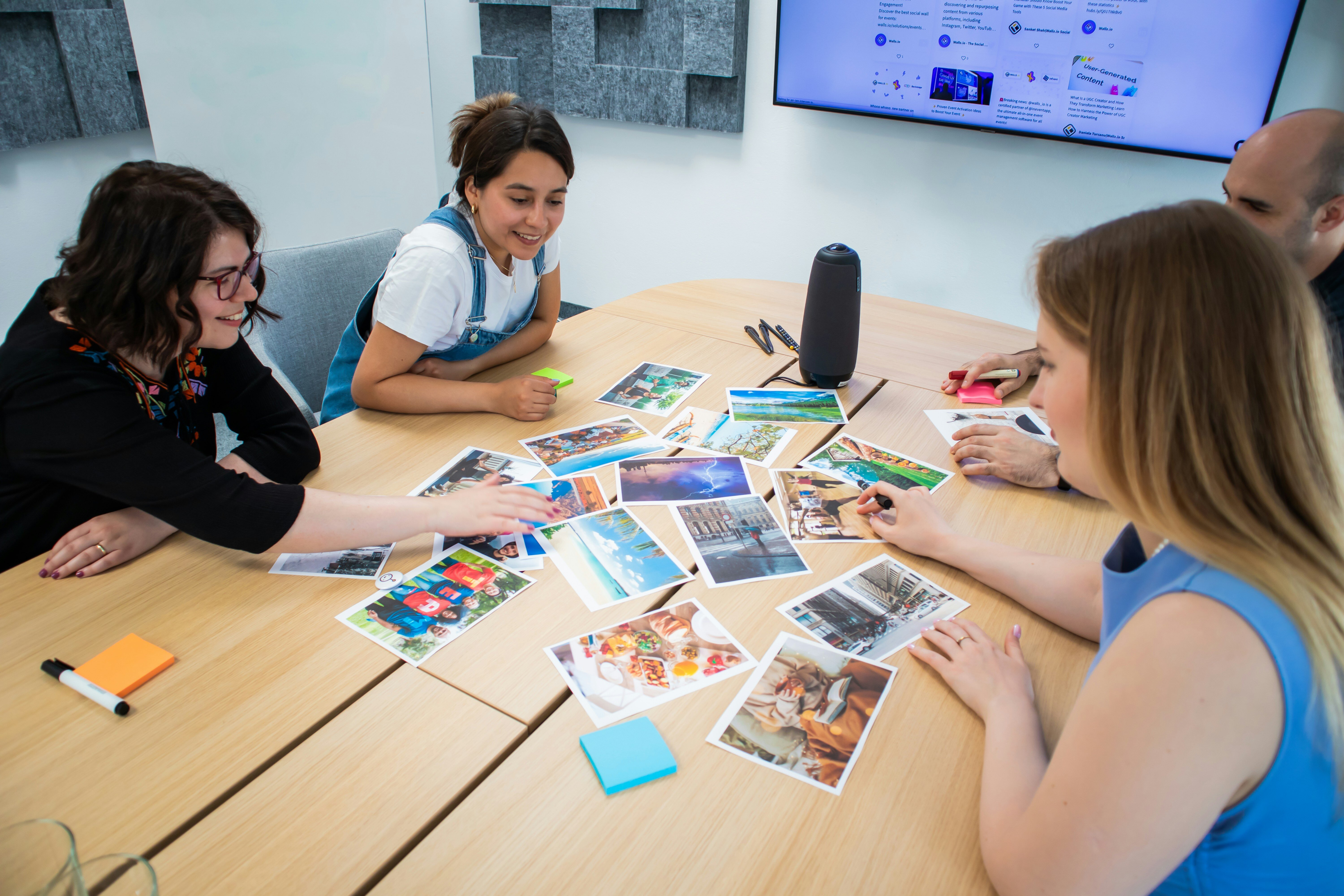 A diverse group of individuals engaged in discussion around a table adorned with various pictures.