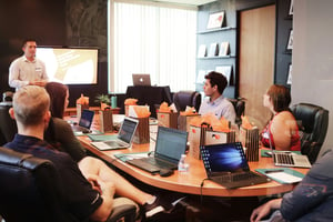 A diverse group of individuals collaborates around a table, each engaged with their laptops in a productive setting.