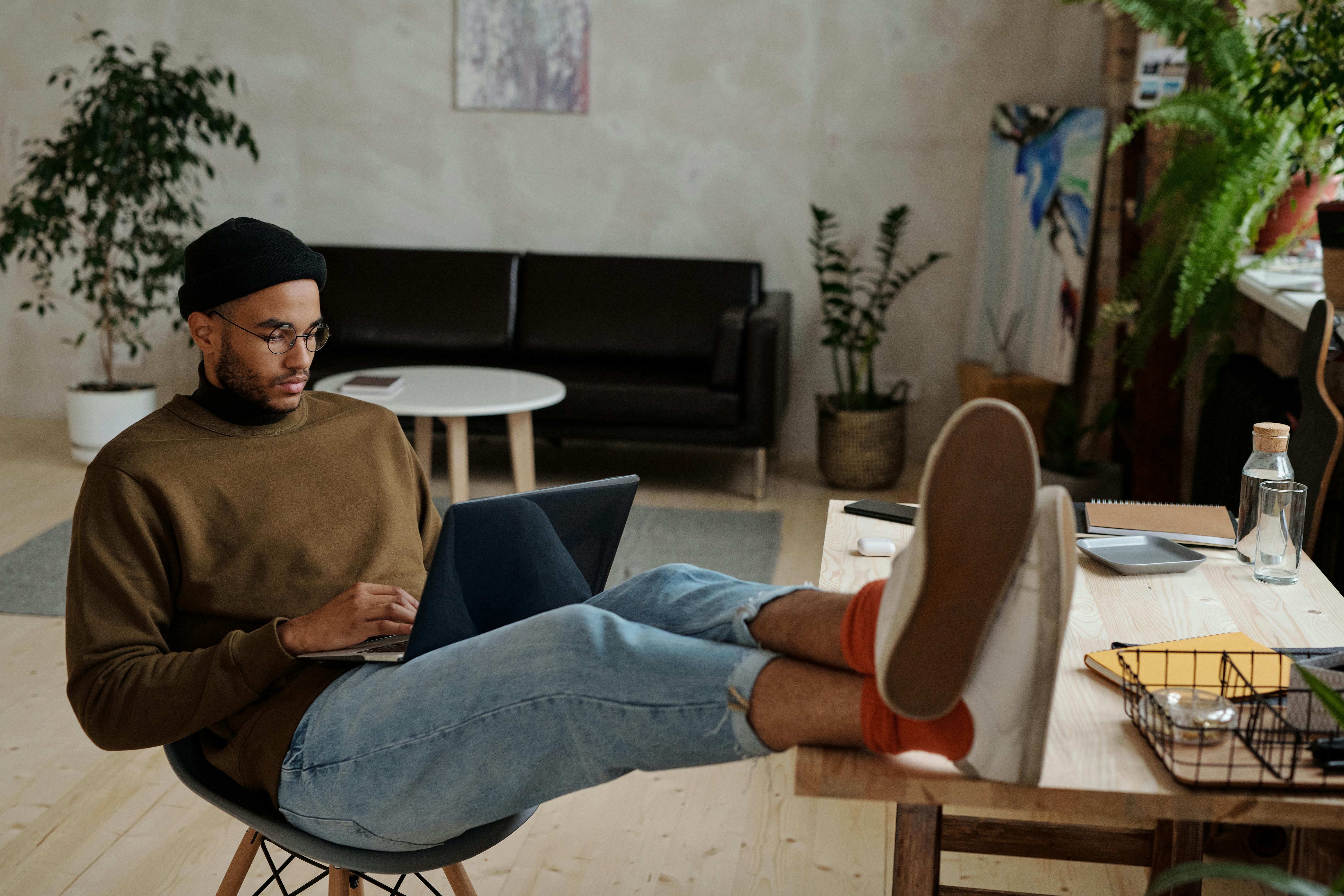 A man relaxes in a chair with his feet on a laptop, enjoying a moment of leisure and comfort.