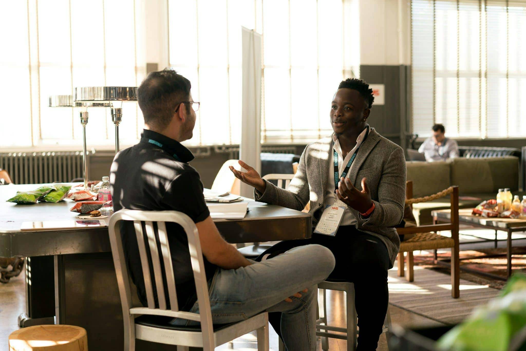 wo men engaged in conversation while seated at a table, sharing ideas and perspectives in a relaxed setting.