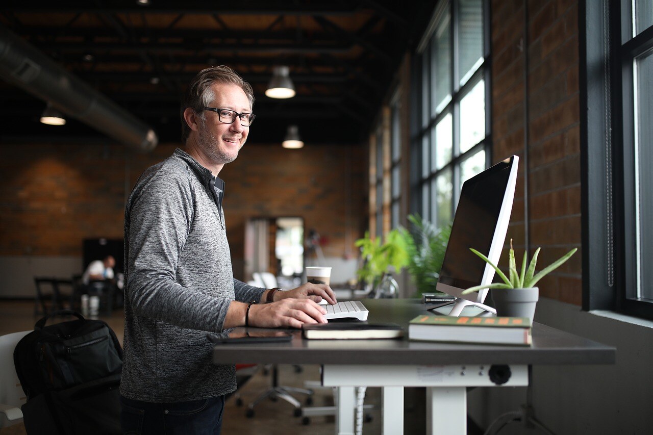 a man sitting on a desk in front of a laptop