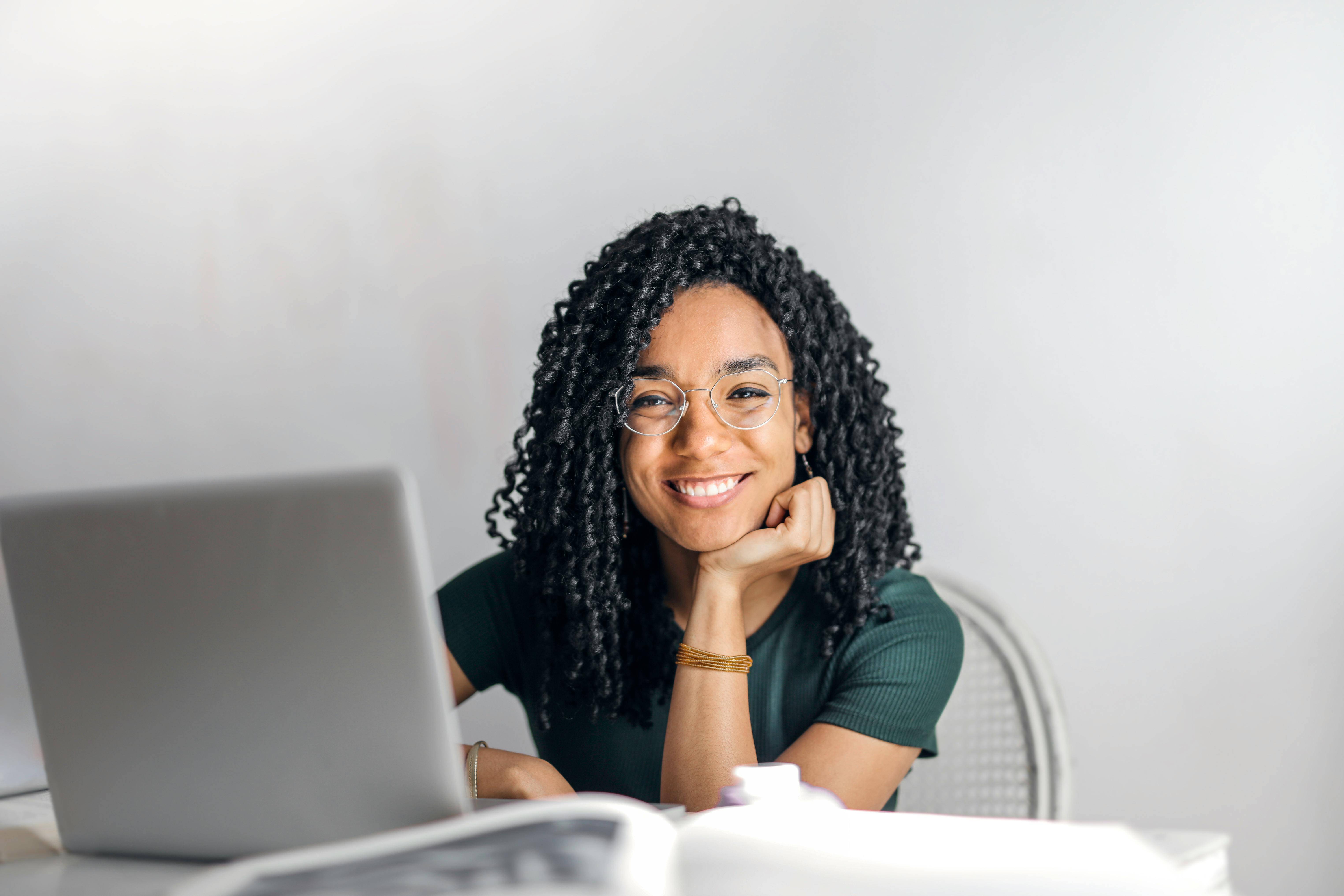 A woman with dreadlocks is seated at a desk, focused on her laptop, creating a productive work environment.